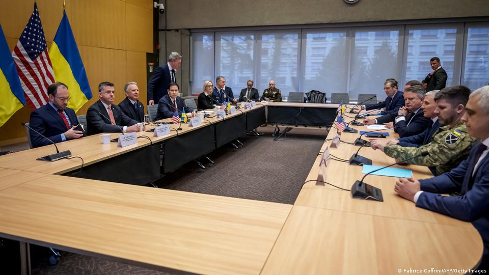  Zwei Delegationen sitzen sich an Tischen gegenüber