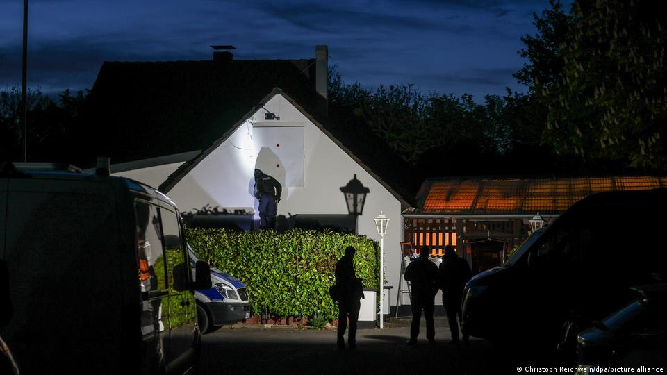 Polizisten stehen im Dunkeln vor einem Gebäude