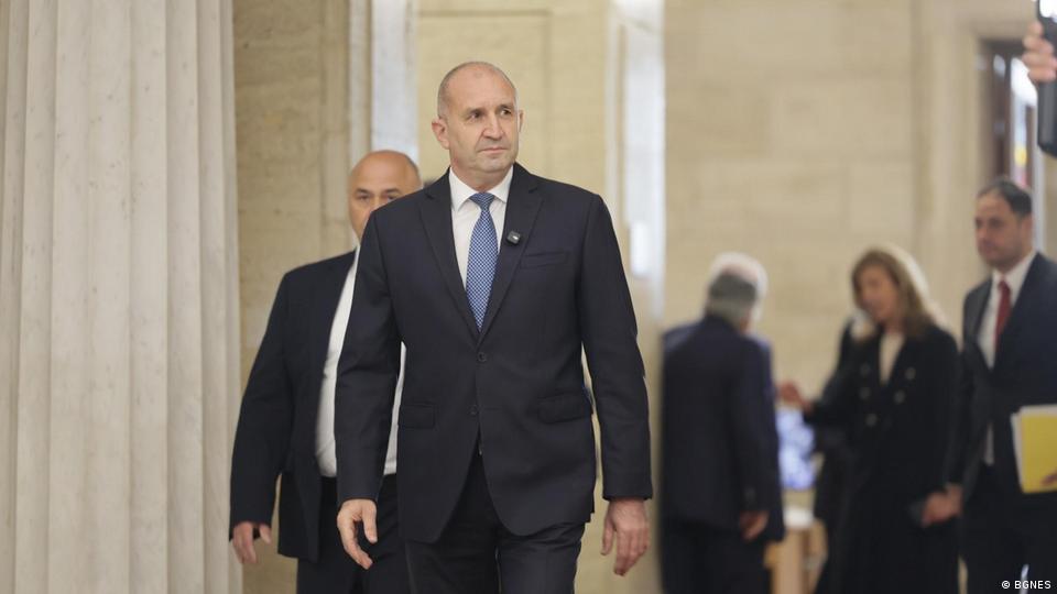 Rumen Radev, ein Mann im dunklen Anzug mit blauer Krawatte, der durch einen Flur läuft, im Hintergrund sind andere Personen zu sehen