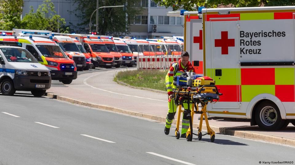 Ein Rettungshelfer schiebt eine Trage an einer Reihe geparkter Krankenwagen vorbei