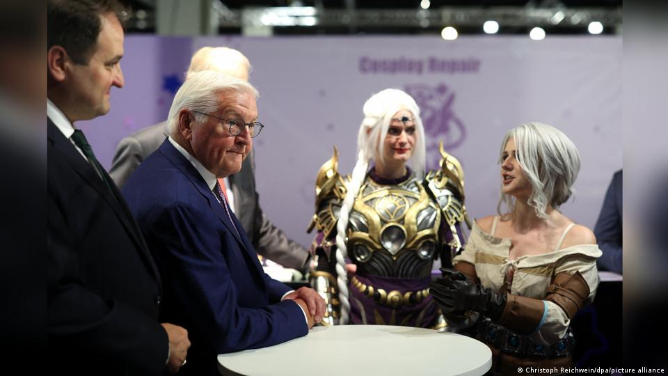 Bundespräsident Frank-Walter Steinmeier und NRW-Minister Nathanael Liminski stehen mit Cosplayern verkleidet als Shadowheart aus Baldur's Gate und Ciri aus The Witcher auf der Gamescom in Köln