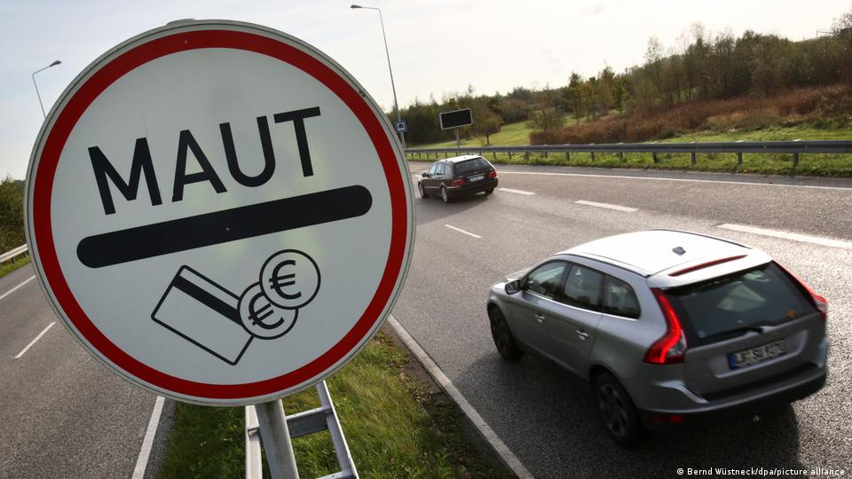 Autos fahren an einem Schild mit der Aufschrift „Maut“ vorbei
