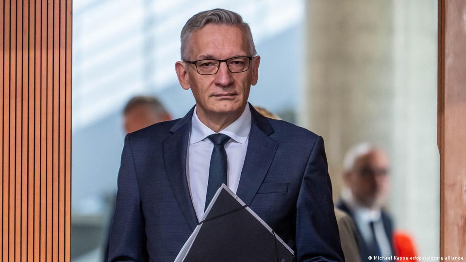 Martin Jäger, bebrillter Mann im blauen Anzug vor offenem Eingang