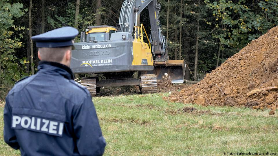 Ein Polizist beobachtet einen Bagger neben einem Erdhaufen