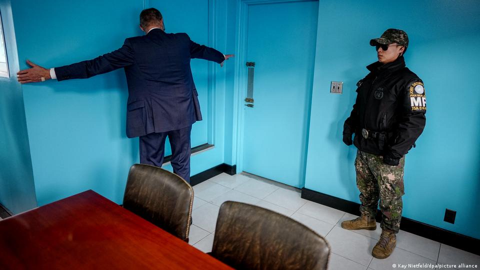 Bundeskanzler Merz streckt seine Arme entlang einer blauen Wand