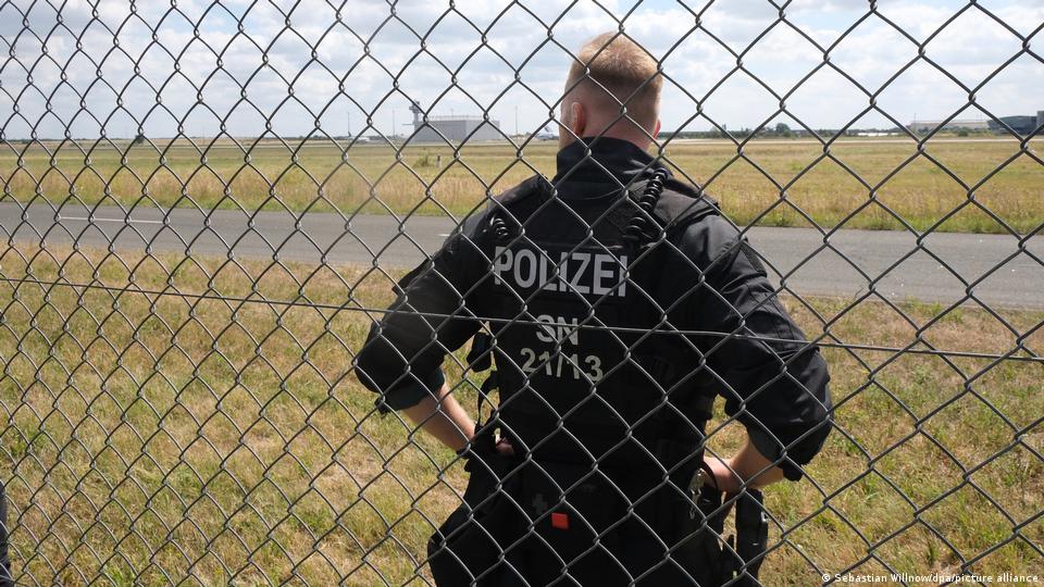Ein Polizist steht am Zaun des Leipziger Flughafens