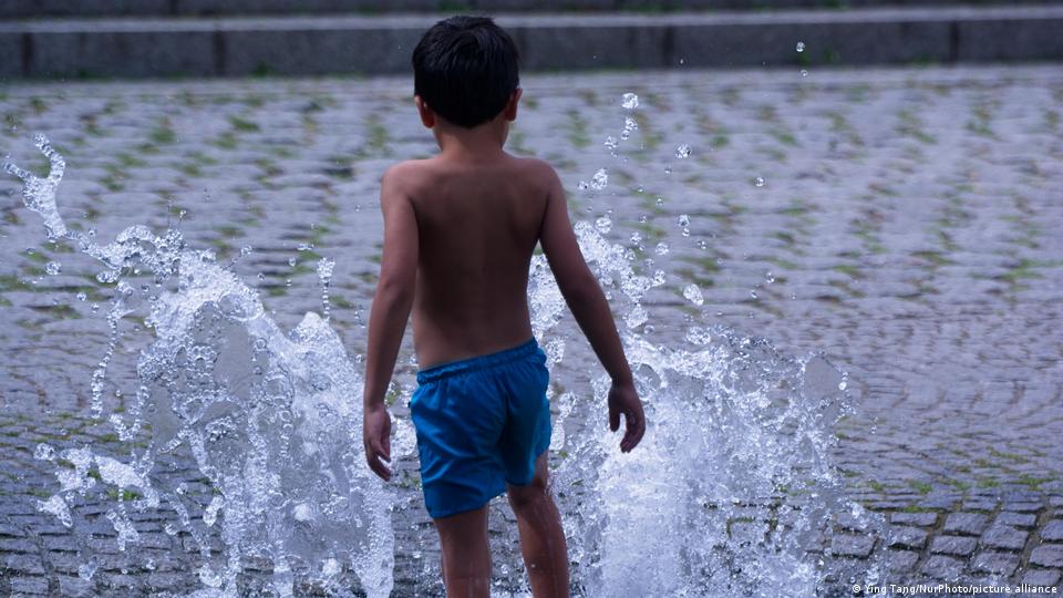 Ein kleiner Junge spielt in einem Wasserbrunnen in Köln
