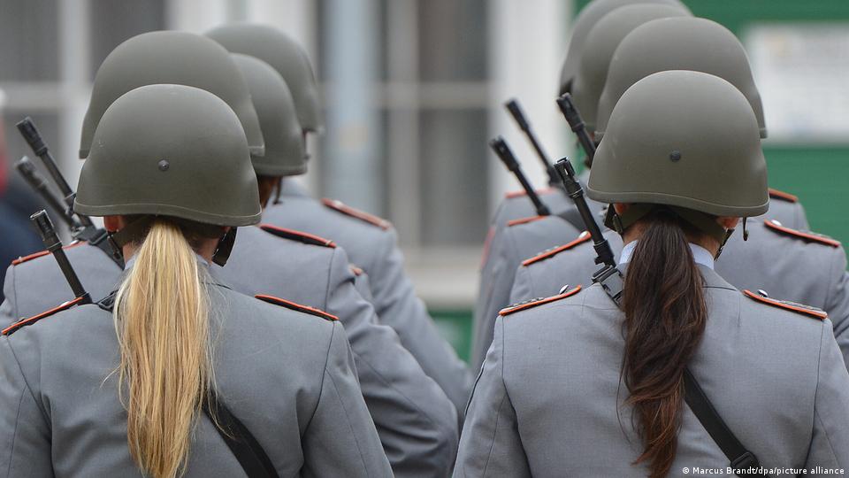 Zwei Soldatinnen stehen hinter anderen Soldaten