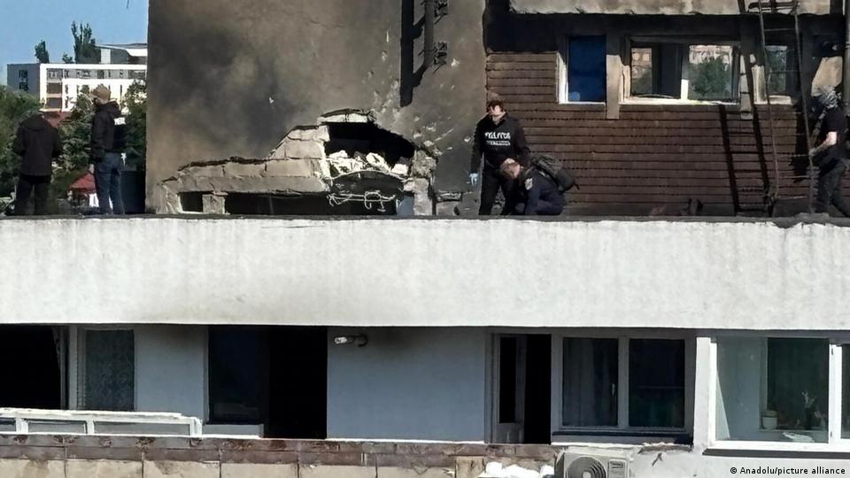 Männer arbeiten in der Nähe eines Lochs in einer rußbedeckten Wand auf einem Gebäude in Rumänien (29. Mai 2026)