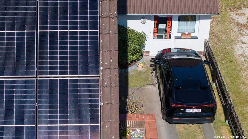Elektroauto wird neben dem Dach mit Solarpaneelen aufgeladen