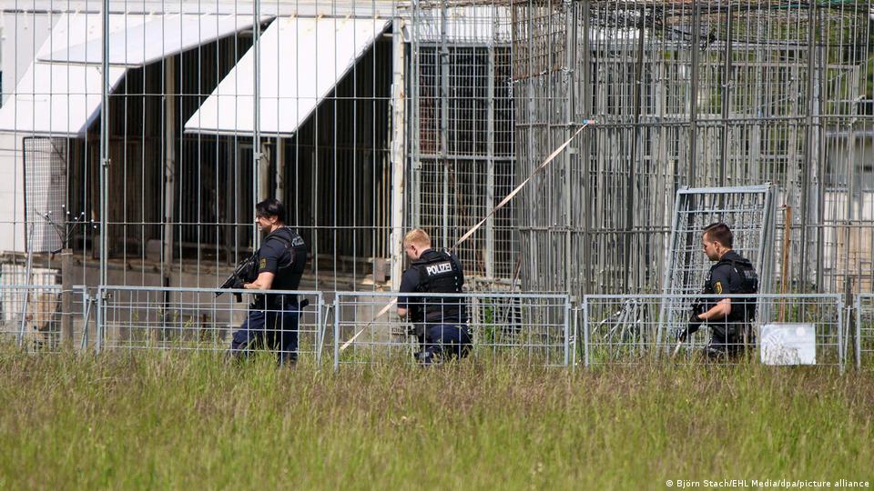 Bewaffnete Polizisten gehen vor Käfigen